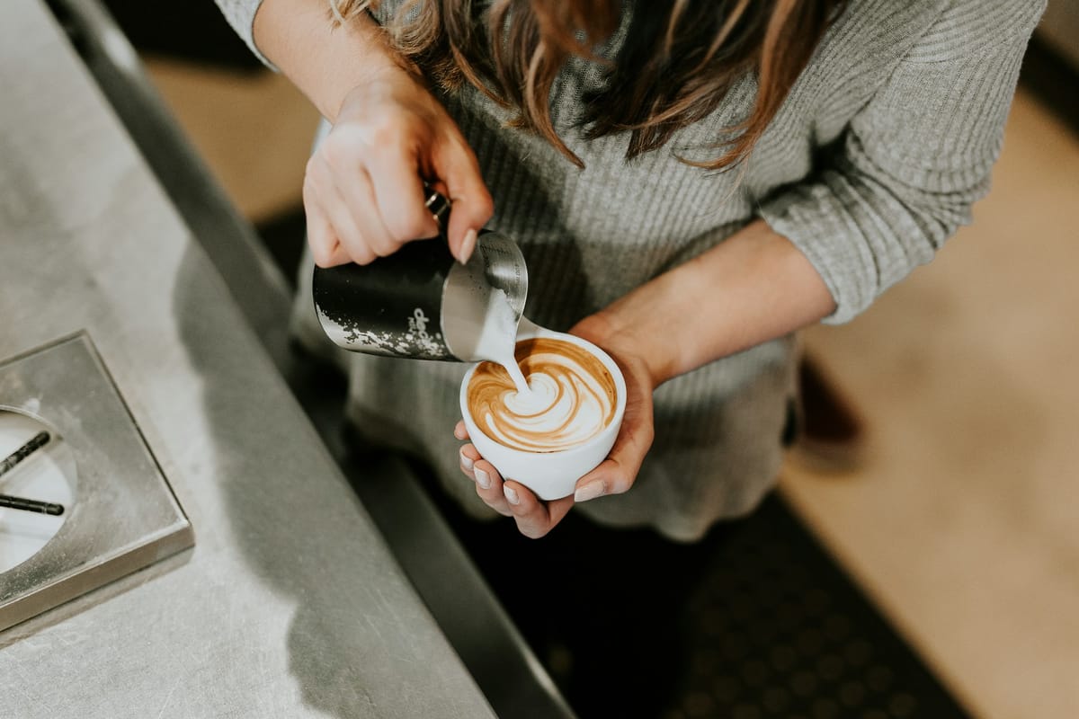 Barista heller melk i en kaffekopp